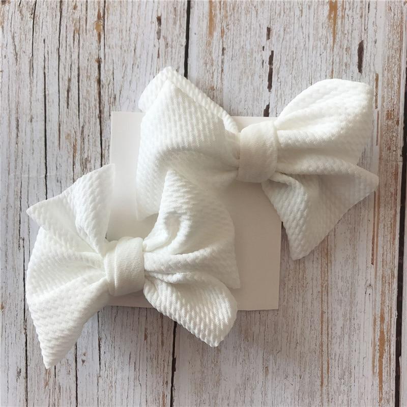 Two white textured bows on a wooden surface. Sold by Little Janey Shop