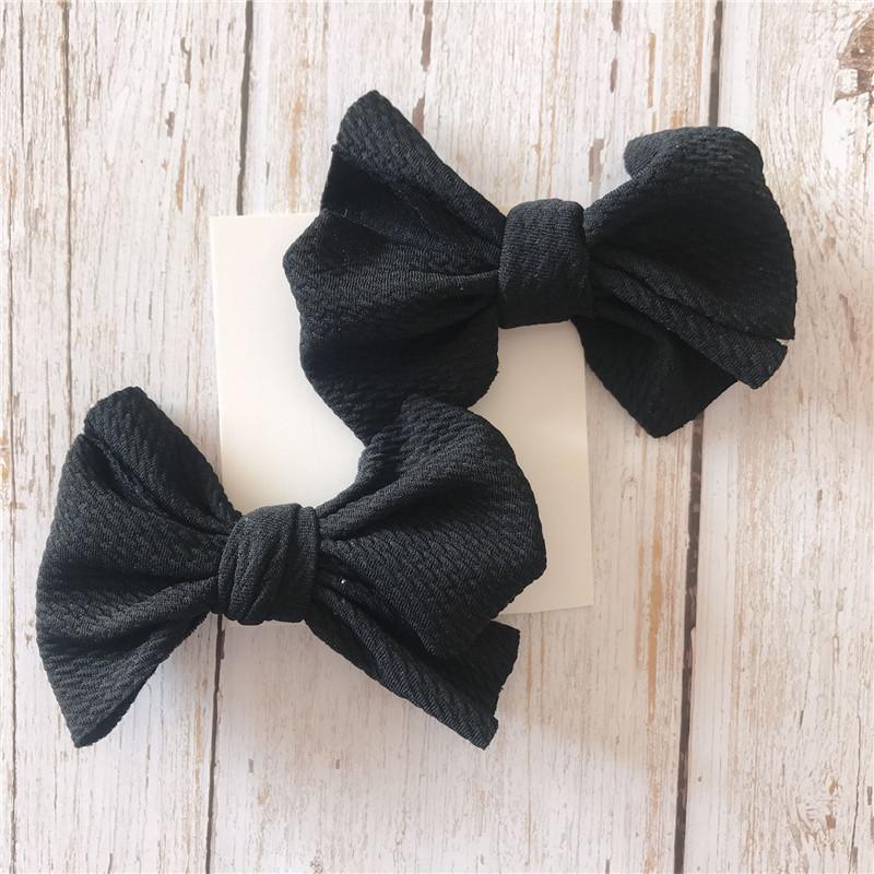 Two black hair Handmade Grosgrain Hair Bow Clips on a light wooden surface. Little Janey Shop.