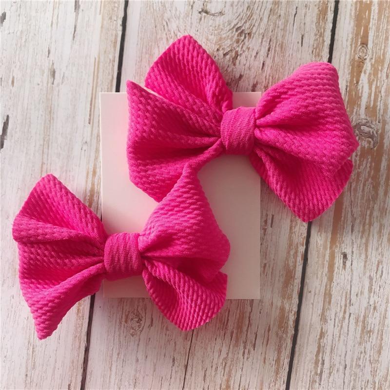 Two pink texturedHandmade Grosgrain Hair Bow Clips  on a wooden surface. Little Janey Shop.