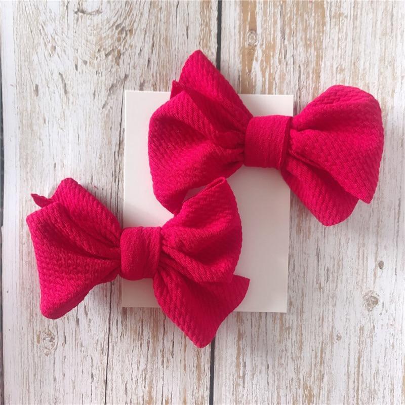 Two red Handmade Grosgrain Hair Bow Clips on a white card with a wooden background. Little Janey Shop