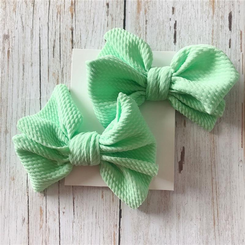 Two green textured bows on a white card with a wooden background