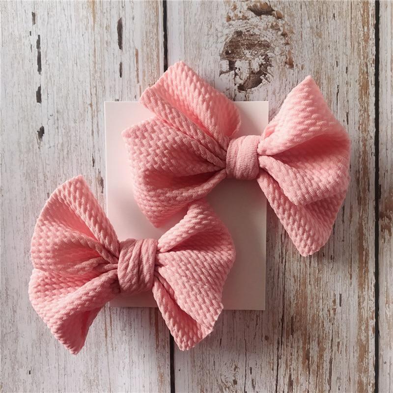 Two pink textured Handmade Grosgrain Hair Bow Clips on a wodden board. Little Janey Shop.