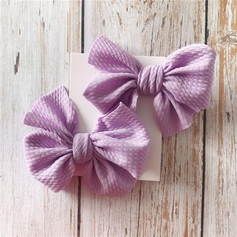 Two purple textured Handmade Grosgrain Hair Bow Clips on a wooden surface. Little Janey Shop.