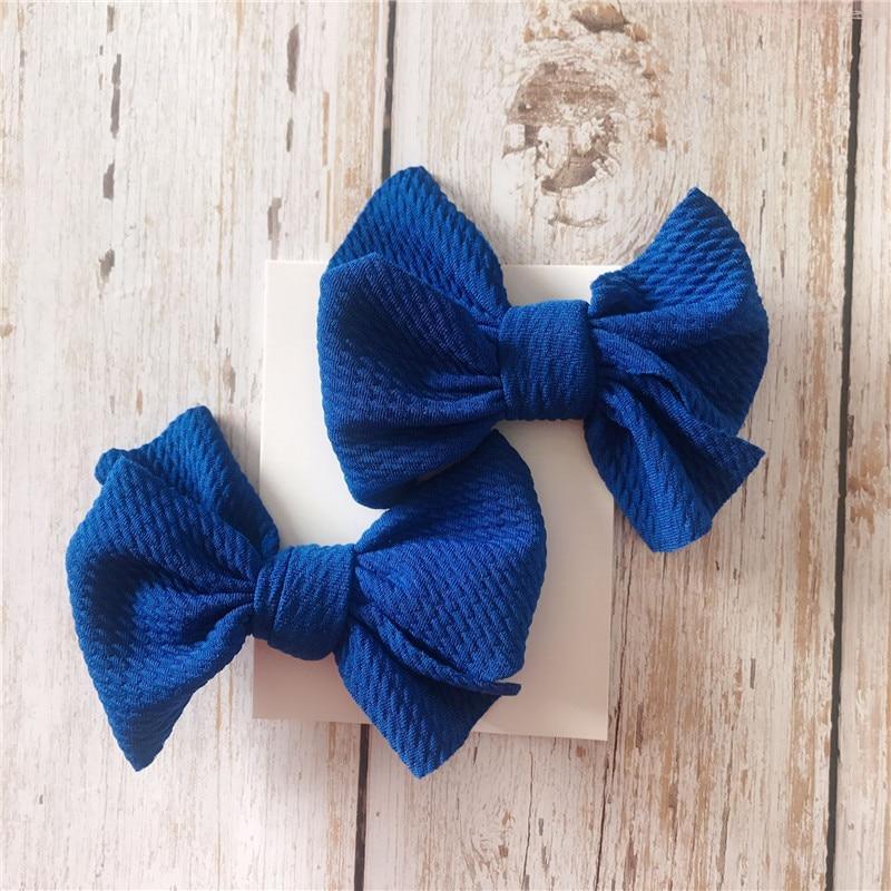 Two blue Handmade Grosgrain Hair Bow Clips on a wooden surface. Little Janey Shop