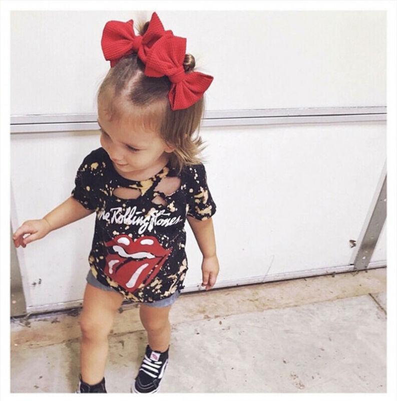 Child wearing a Rolling Stones-themed outfit with a red bow in hair.