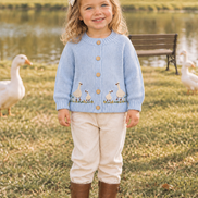 Two-year-old toddler wearing the goose cardigan on the same farm scene